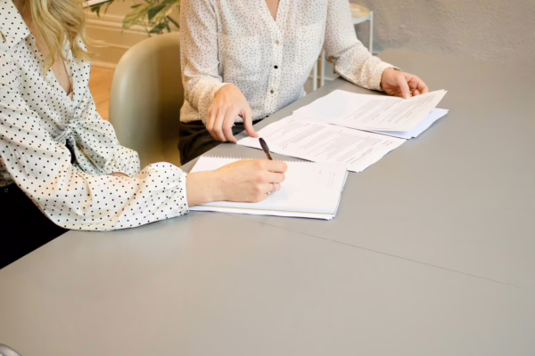 Incorporated Societies Re-registration: two women look at and exchange pieces of paper to sign.
